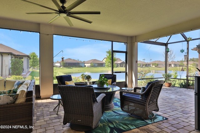 sunroom with ceiling fan and a water view