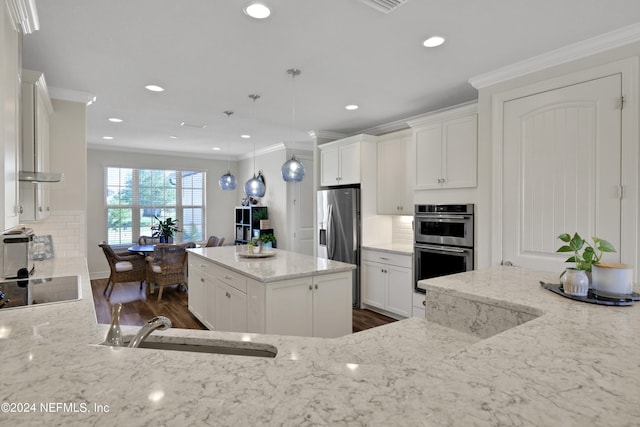 kitchen featuring backsplash, a center island, appliances with stainless steel finishes, and decorative light fixtures