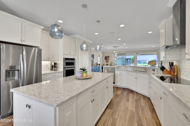 kitchen with backsplash, light hardwood / wood-style flooring, stainless steel appliances, wall chimney exhaust hood, and pendant lighting