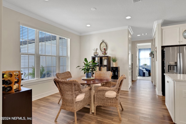 dining room with hardwood / wood-style floors, plenty of natural light, and ornamental molding