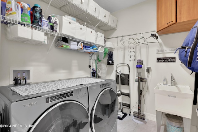 washroom featuring light tile flooring, washer and clothes dryer, washer hookup, sink, and cabinets