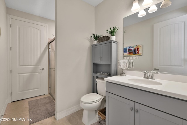 bathroom with tile flooring, vanity with extensive cabinet space, toilet, and a shower with shower door