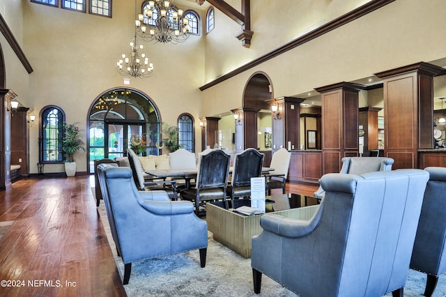 interior space featuring a notable chandelier, dark hardwood / wood-style flooring, decorative columns, and a high ceiling