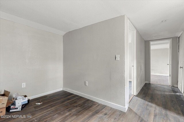 empty room with dark hardwood / wood-style flooring and a textured ceiling