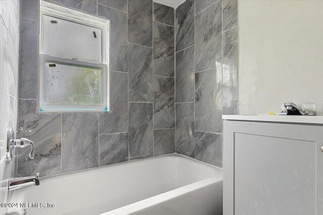 bathroom featuring tiled shower / bath and vanity