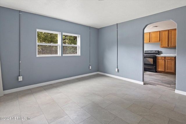 tiled empty room featuring a textured ceiling