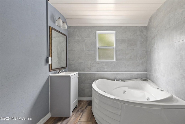 bathroom featuring tile walls, vanity, hardwood / wood-style flooring, and a bath