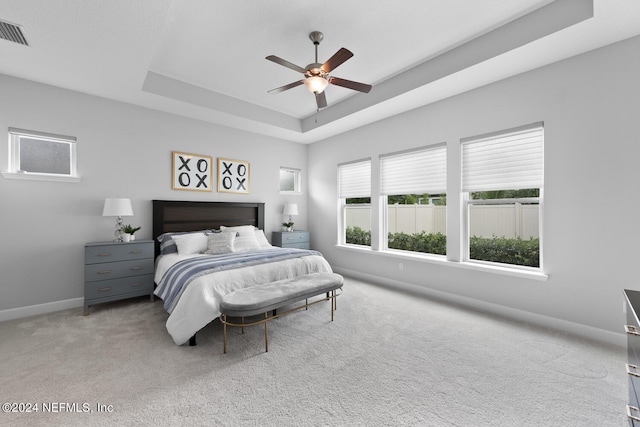 carpeted bedroom featuring a tray ceiling and ceiling fan