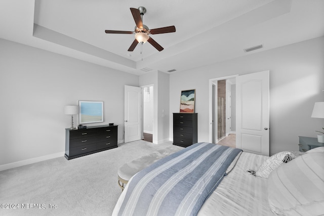 bedroom with carpet, ceiling fan, a raised ceiling, and ensuite bathroom