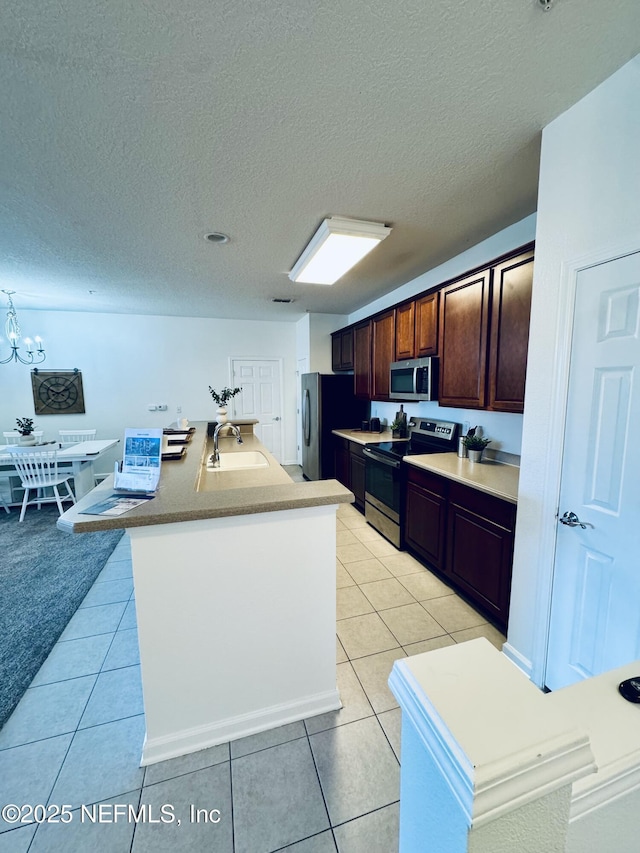 kitchen featuring light tile patterned floors, stainless steel appliances, a sink, and an inviting chandelier