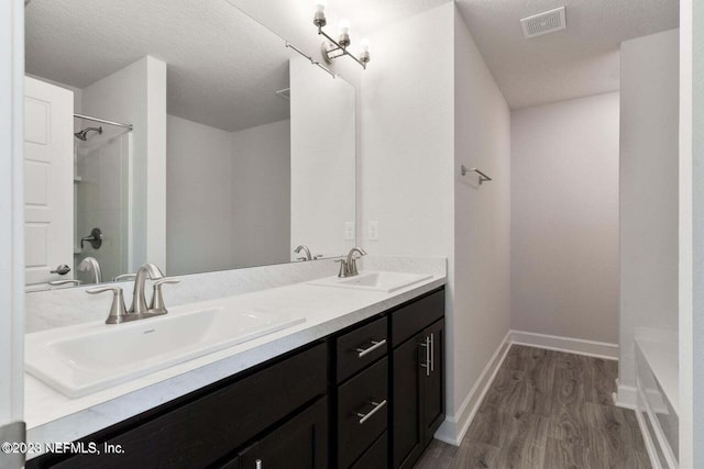 bathroom with hardwood / wood-style floors, vanity, a textured ceiling, and walk in shower