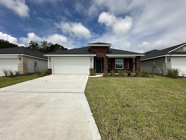 view of front of property featuring an attached garage, driveway, brick siding, and a front yard