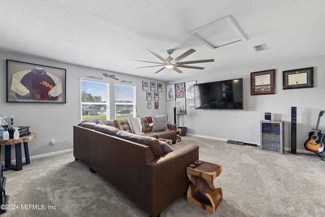 carpeted living room featuring ceiling fan and a textured ceiling