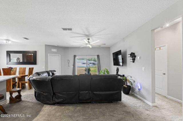 carpeted living room featuring a textured ceiling and ceiling fan