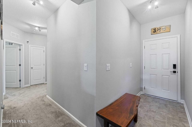 interior space with rail lighting, light tile floors, and a textured ceiling