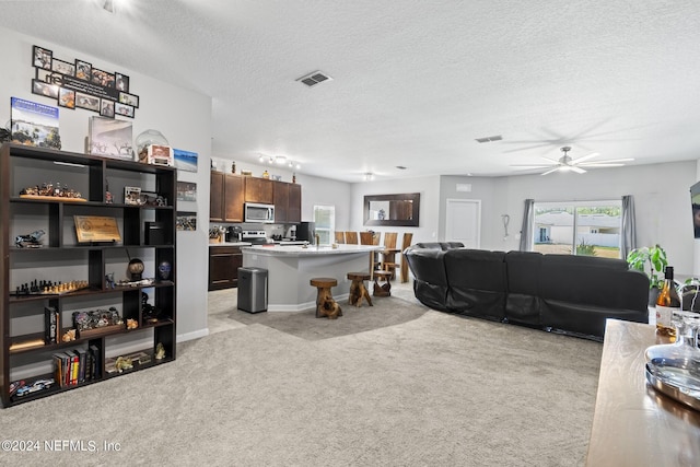 living room with light colored carpet, ceiling fan, and a textured ceiling