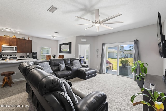 carpeted living room featuring a textured ceiling, ceiling fan, and track lighting