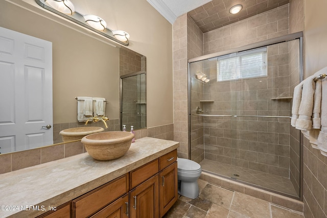 bathroom featuring vanity, toilet, a shower with door, and ornamental molding