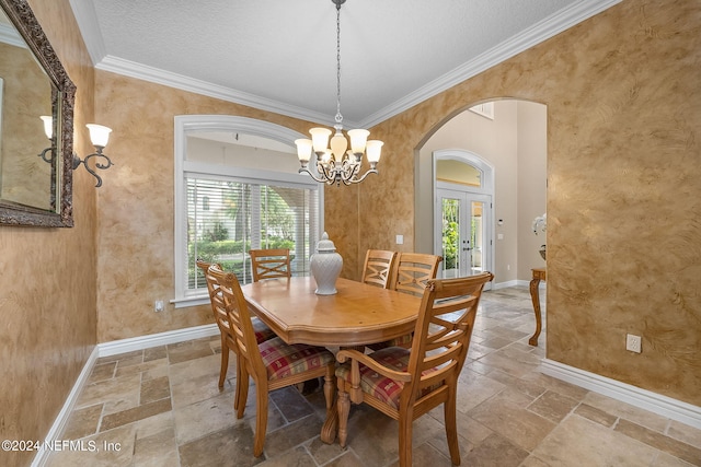 dining area with french doors, a textured ceiling, an inviting chandelier, and ornamental molding