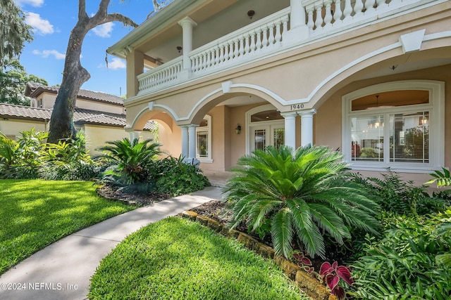 entrance to property featuring a yard and a balcony