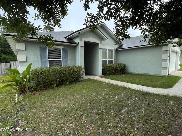 view of front of property featuring a garage, a shingled roof, stucco siding, fence, and a front yard