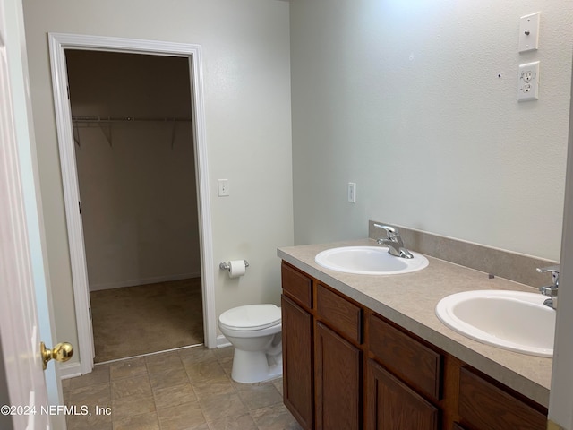 bathroom with a sink, a spacious closet, toilet, and double vanity