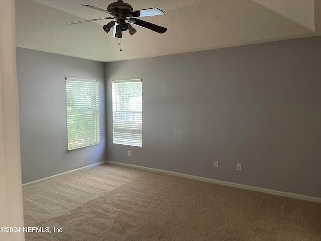 empty room featuring a textured ceiling, ceiling fan, carpet, and baseboards