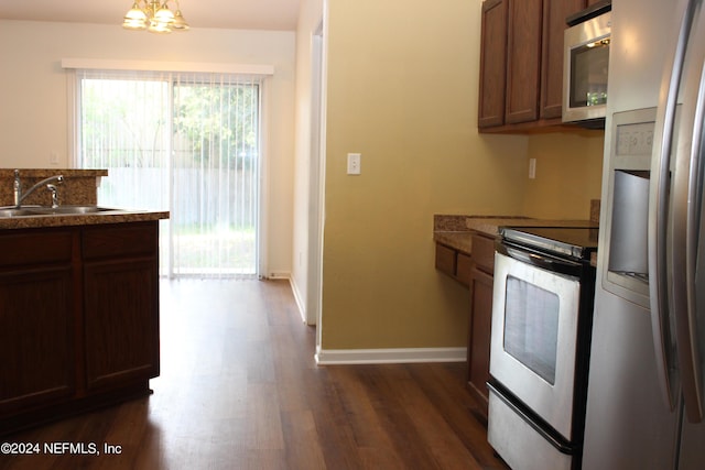 kitchen with baseboards, appliances with stainless steel finishes, dark wood finished floors, and a sink