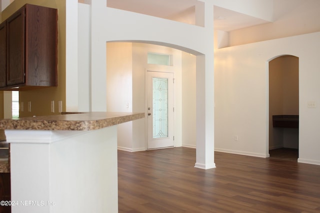 kitchen with baseboards, dark wood-style flooring, a peninsula, light countertops, and dark brown cabinets