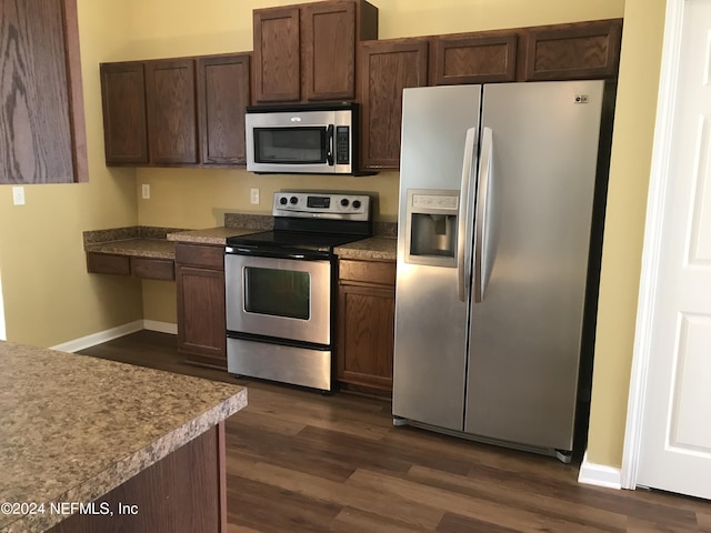 kitchen featuring stainless steel appliances, dark brown cabinets, dark wood-style flooring, and baseboards