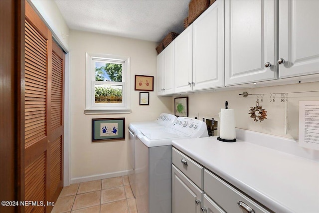 washroom featuring a textured ceiling, light tile patterned flooring, baseboards, independent washer and dryer, and cabinet space