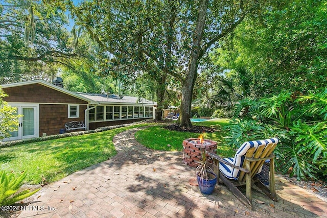 view of yard with french doors, an outdoor fire pit, a sunroom, and a patio area