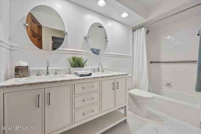 bathroom featuring toilet, double vanity, tile walls, and a sink