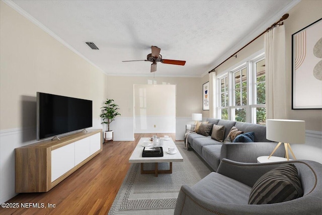 living room with visible vents, crown molding, a textured ceiling, and wood finished floors