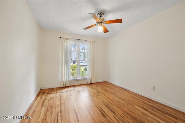 empty room featuring light wood finished floors, a textured ceiling, baseboards, and a ceiling fan