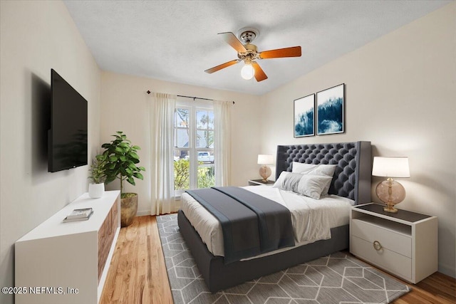 bedroom featuring light wood finished floors, a textured ceiling, and a ceiling fan