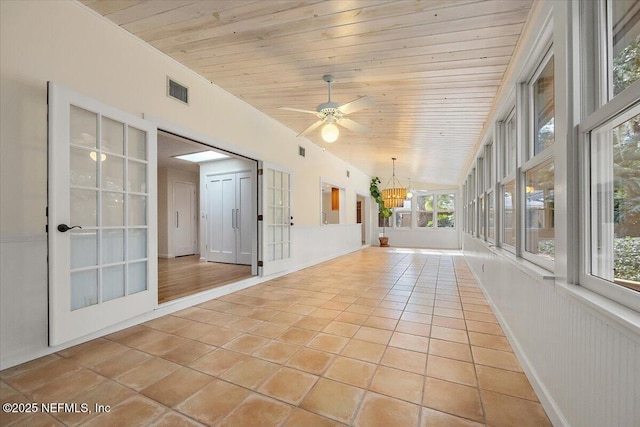 unfurnished sunroom featuring ceiling fan with notable chandelier and wooden ceiling