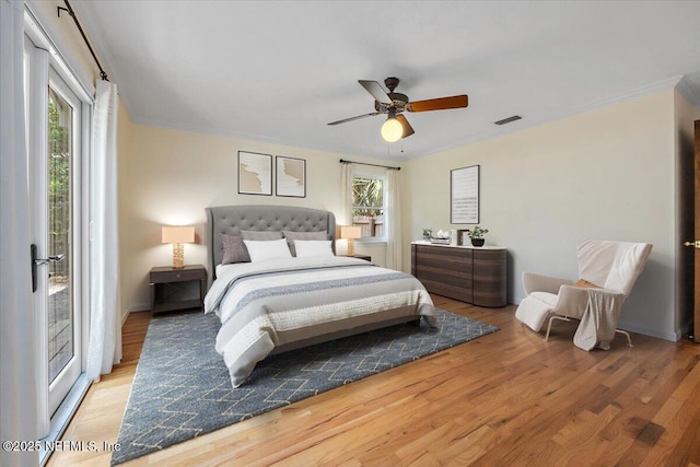 bedroom featuring ceiling fan, multiple windows, wood finished floors, and visible vents