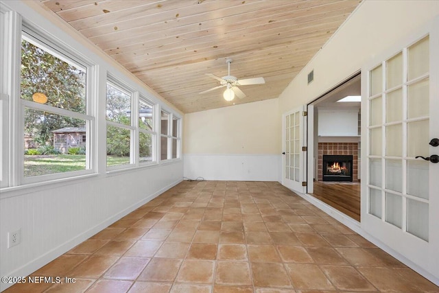 unfurnished sunroom featuring french doors, a fireplace, visible vents, a ceiling fan, and wooden ceiling