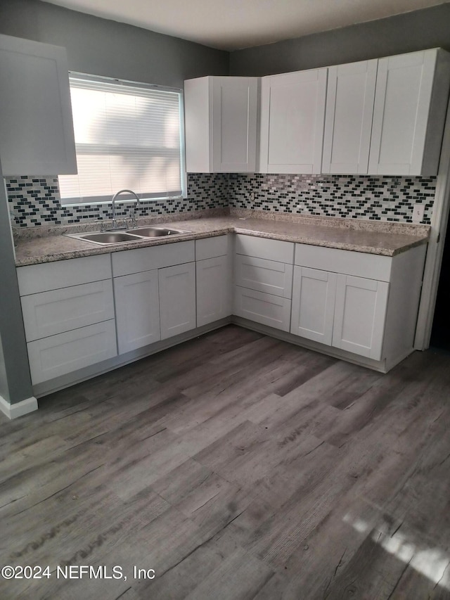 kitchen featuring hardwood / wood-style floors, sink, tasteful backsplash, and white cabinets