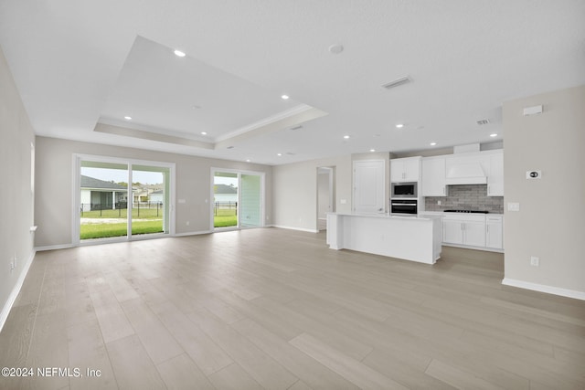 unfurnished living room featuring light hardwood / wood-style flooring and a tray ceiling