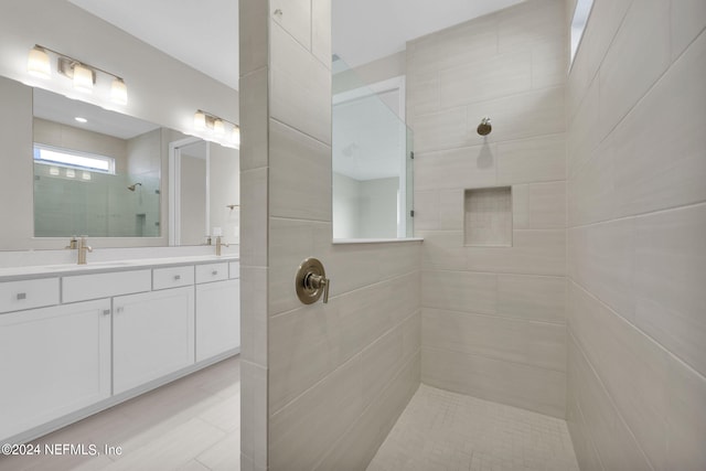 bathroom with tile walls, vanity, tile patterned floors, and tiled shower