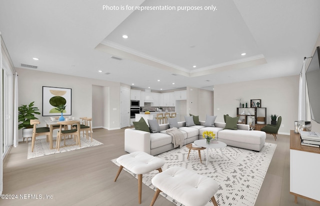 living room with ornamental molding, light hardwood / wood-style flooring, and a tray ceiling