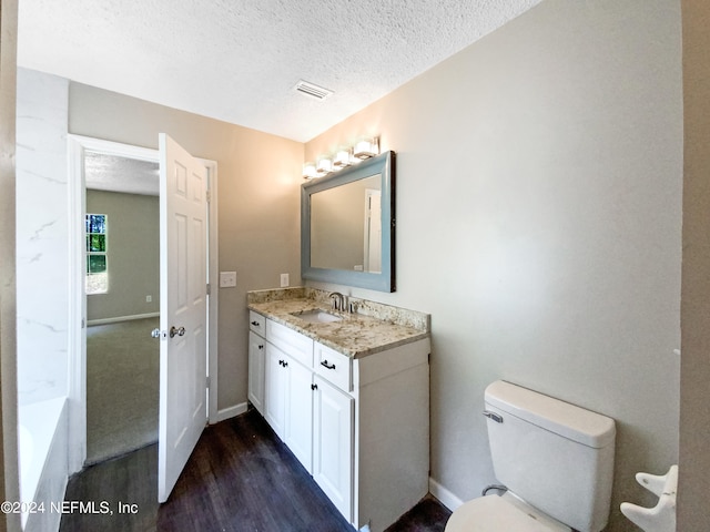 bathroom featuring hardwood / wood-style flooring, toilet, vanity, and a textured ceiling