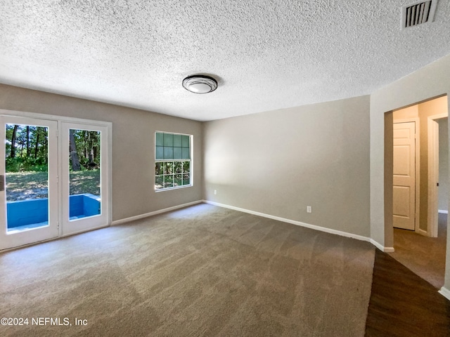 spare room featuring carpet flooring and a textured ceiling