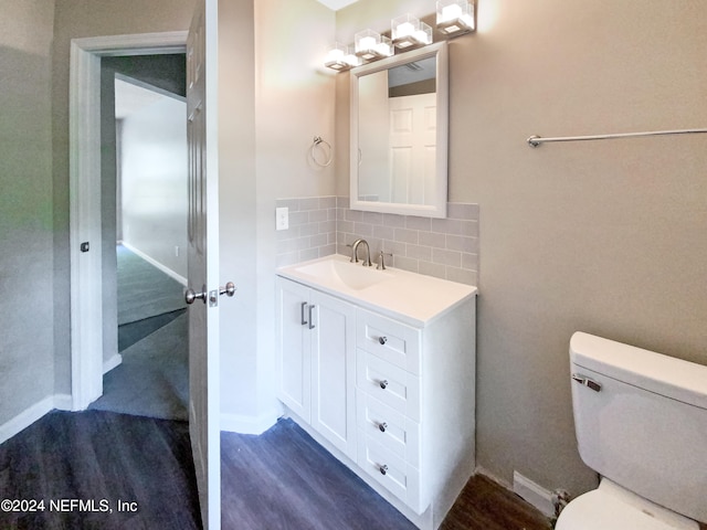 bathroom with wood-type flooring, vanity, tasteful backsplash, and toilet