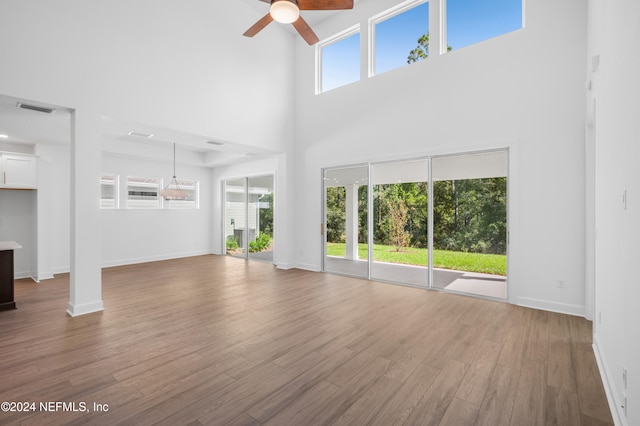 unfurnished living room featuring a towering ceiling, plenty of natural light, and wood-type flooring