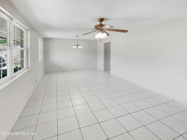 unfurnished room with ceiling fan with notable chandelier, a textured ceiling, and light tile flooring