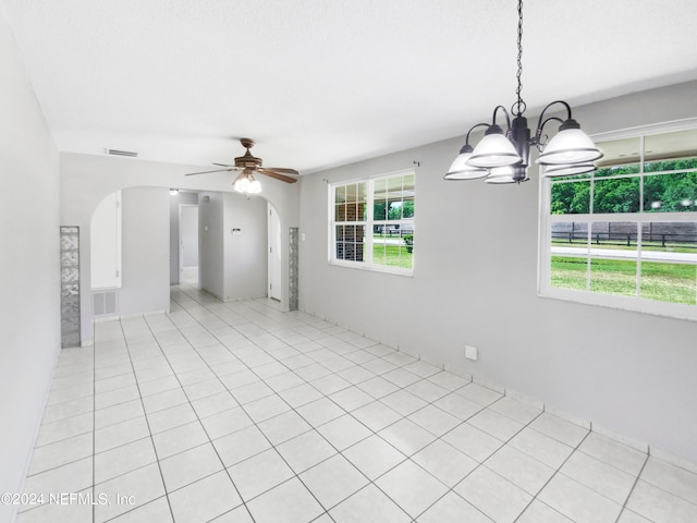 unfurnished room with a healthy amount of sunlight, light tile floors, and ceiling fan with notable chandelier