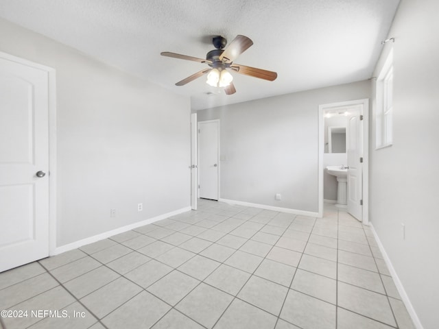 empty room featuring sink, a textured ceiling, ceiling fan, and light tile floors